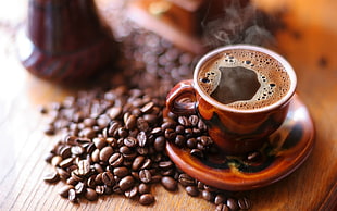 brown ceramic coffee mug with coffee beans beside